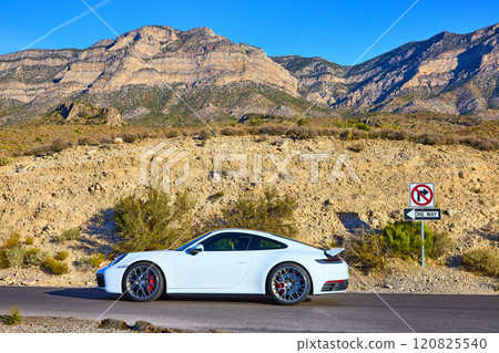Sleek White Sports Car on Desert Road with Mountain Backdrop Eye-Level View Sleek White Sports Car on Desert Road with Mountain Backdrop Eye-Level View 120825540