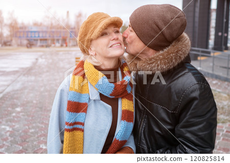 Elderly man kissing woman on cheek while walking in winter city 120825814
