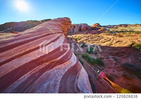 Fire Wave Rock Formation in Sunlit Desert Valley Low Angle View 120826816