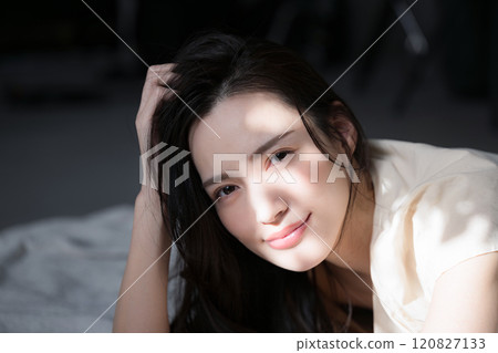 Cosmetic and beauty image of a beautiful woman relaxing in the sunlight with beautiful shadows, looking at the camera 120827133