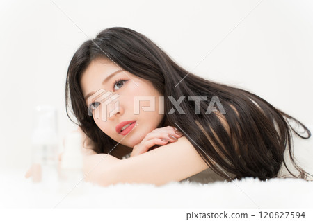 Beauty image: A young woman lying down in front of a cosmetic container Beauty image: A young woman lying down in front of a cosmetic container 120827594