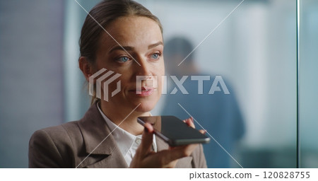 Female marketing manager records voice message in app using smartphone 120828755