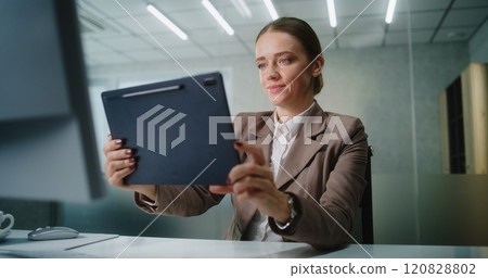 Businesswoman chatting with business partner via video call using tablet computer 120828802