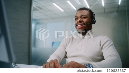 African American marketing specialist talks on headset with client, uses computer 120828887