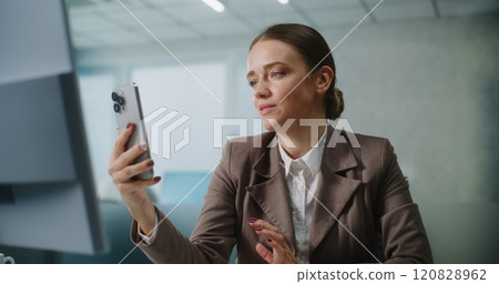 Businesswoman chatting with business partner on video call using smartphone Businesswoman chatting with business partner on video call using smartphone 120828962