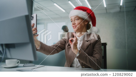 Businesswoman in Christmas hat talks to business partner on video call using smartphone Businesswoman in Christmas hat talks to business partner on video call using smartphone 120829002