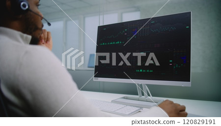 Stock exchange trader talks on headset, monitors equity market and shares using computer 120829191