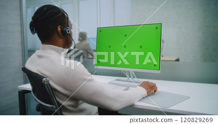 African American financial expert wearing headset works on computer with green screen chromakey 120829269