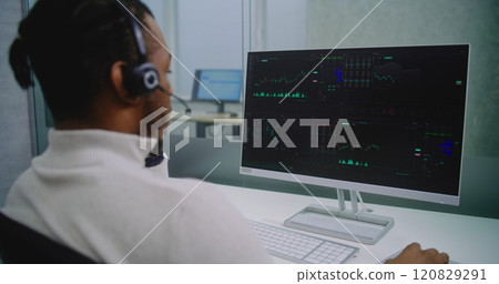 African American financial specialist in headset analyzes share market and stocks on computer 120829291