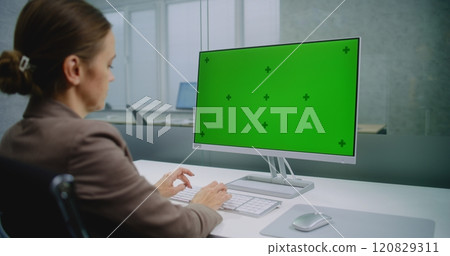 Professional female financial expert enters data using computer with green screen chroma key 120829311