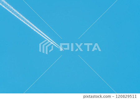 An airplane flying in the blue sky and a trail of contrails 120829511