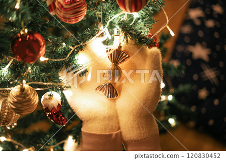 Christmas tree, white gloves holding balls and Christmas tree decorations with small lights 120830452