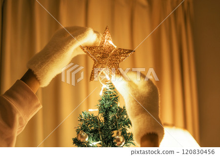 Hands decorating a Christmas tree star in the bedroom 120830456