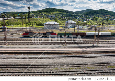The freight train passes through the railway station in the village 120832109