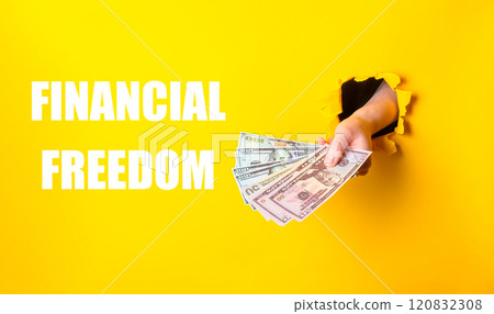 A hand holding a stack of money with the words financial freedom written below 120832308