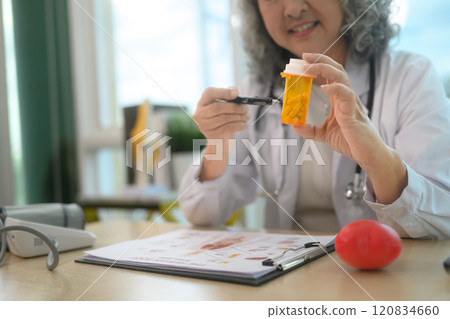 Smiling senior female doctor providing detailed explanations about prescription during a consultation 120834660