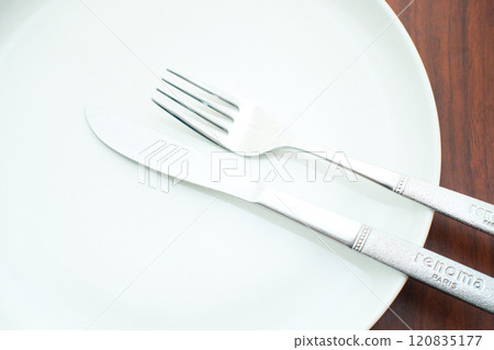 Wait for the next dish by green dish and cutlery placed on a brown table Wait for the next dish by green dish and cutlery placed on a brown table 120835177