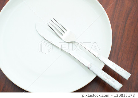 Wait for the next dish by green dish and cutlery placed on a brown table Wait for the next dish by green dish and cutlery placed on a brown table 120835178