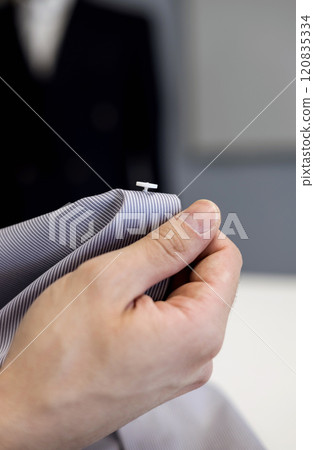 tailor holds a shirt with sewn button tailor holds a shirt with sewn button 120835334