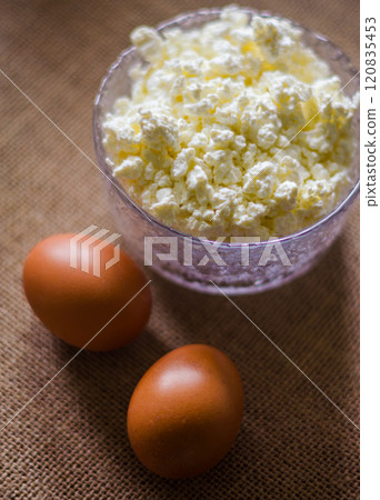 cottage cheese in glass bowl with two eggs on beige background . High quality photo cottage cheese in glass bowl with two eggs on beige background . High quality photo 120835453