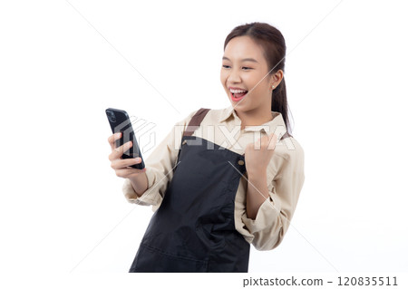 Portrait happy young asian barista woman in apron while looking smart phone gesture success. 120835511