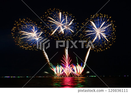Multi-colored fireworks are launched in the middle of the sea from a large steel ship . Multi-colored fireworks are launched in the middle of the sea from a large steel ship . 120836111
