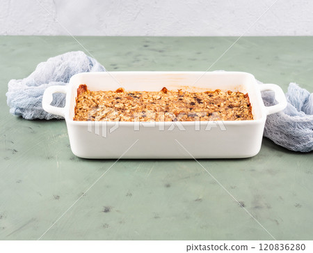 Oatmeal porridge granola cake in white baking tray on green 120836280