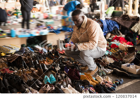 Ordinary african american guy sells sacond hands shoes at flea market Ordinary african american guy sells sacond hands shoes at flea market 120837014