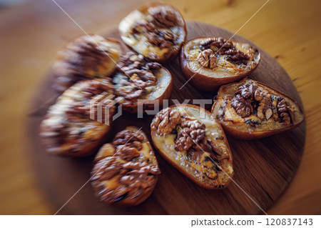 Baked pears topped with walnuts and blue cheese, capturing a rustic and comforting feel 120837143