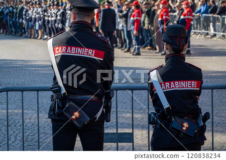 Two carabinieri officers monitoring a public event behind a barricade 120838234