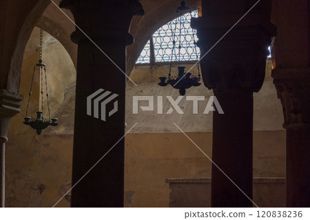 Dimly lit ancient interior with ornate hanging chandeliers and stone columns 120838236