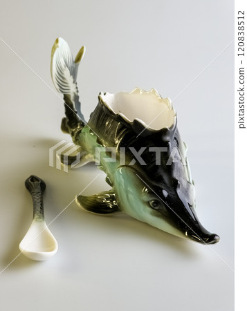 Caviar bowl with a spoon in the shape of a sturgeon on a white background. Specialized original dishes. Caviar bowl with a spoon in the shape of a sturgeon on a white background. Specialized original dishes. 120838512