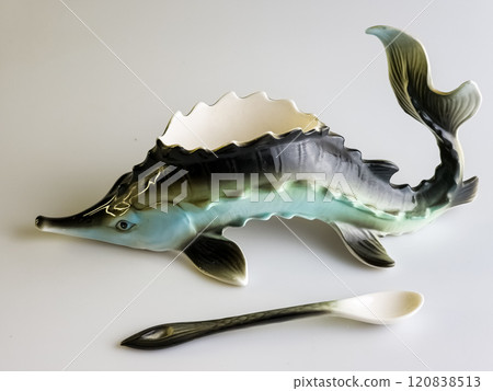 Caviar bowl with a spoon in the shape of a sturgeon on a white background. Specialized original dishes. Caviar bowl with a spoon in the shape of a sturgeon on a white background. Specialized original dishes. 120838513