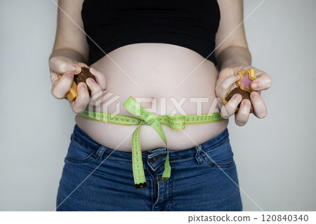 Obesity and overweight from overeating. Big belly tied with measuring tape as a gift. Body fat from candies and sweets 120840340