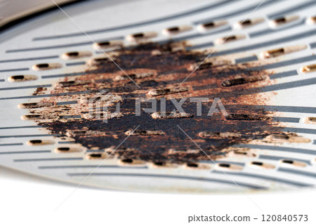 Close-up of a burned steam iron soleplate with visible scorch marks, residue and textured surface Close-up of a burned steam iron soleplate with visible scorch marks, residue and textured surface 120840573
