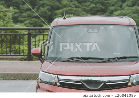 Young woman sitting in the driver's seat of a red car 120841089