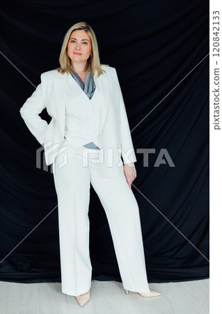 Business woman 45 years old in white business suit on black background 120842133