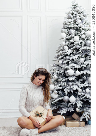 Beautiful woman at a Christmas tree decorated with garlands and gifts for the new year Beautiful woman at a Christmas tree decorated with garlands and gifts for the new year 120843056