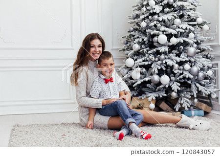 Mother and son at Christmas tree decorated with garlands and gifts for the new year Mother and son at Christmas tree decorated with garlands and gifts for the new year 120843057