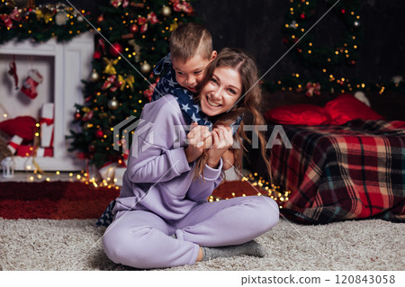 Mother and son at Christmas tree decorated with garlands and gifts for the new year Mother and son at Christmas tree decorated with garlands and gifts for the new year 120843058