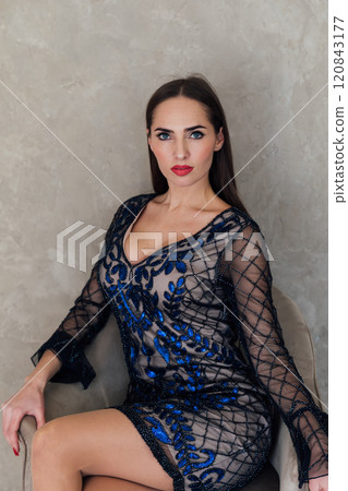 Beautiful slim fashion woman in dress sitting in chair 120843177