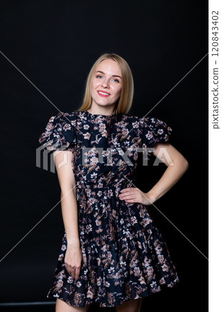 Beautiful blonde woman smiling in dress on black background 120843402