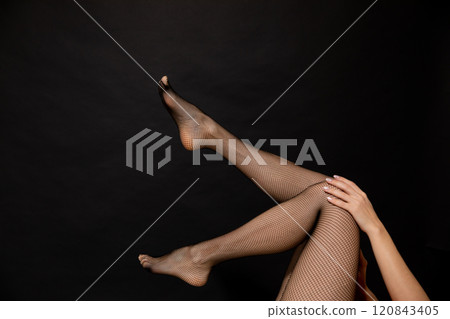 Slender female legs in stockings pantyhose on a black background Slender female legs in stockings pantyhose on a black background 120843405