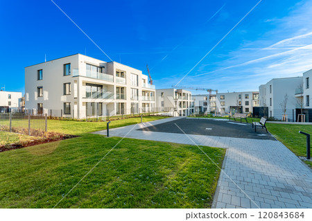 Modern residential complex with green areas and construction crane on sunny day 120843684