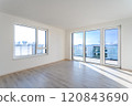 Empty living room with laminate floor and french windows offering city view 120843690