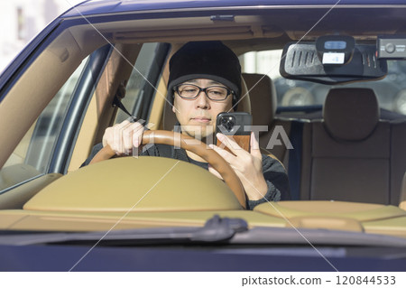 Image of distracted driving (man staring at smartphone) Image of distracted driving (man staring at smartphone) 120844533