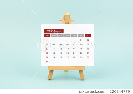 Calendar page for August 2025 with wood easel on a blue background. 120844779