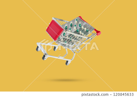 Medicine pills capsule in shopping cart isolated on yellow background 120845633