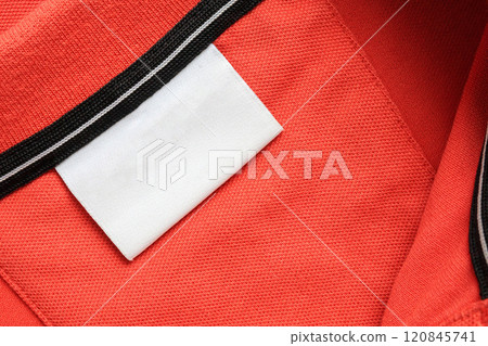 Blank white laundry care clothes label on orange shirt fabric texture background Blank white laundry care clothes label on orange shirt fabric texture background 120845741
