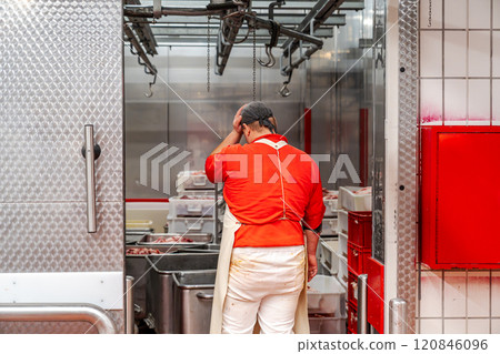Butcher touching head entering cold storage room in slaughterhouse Butcher touching head entering cold storage room in slaughterhouse 120846096